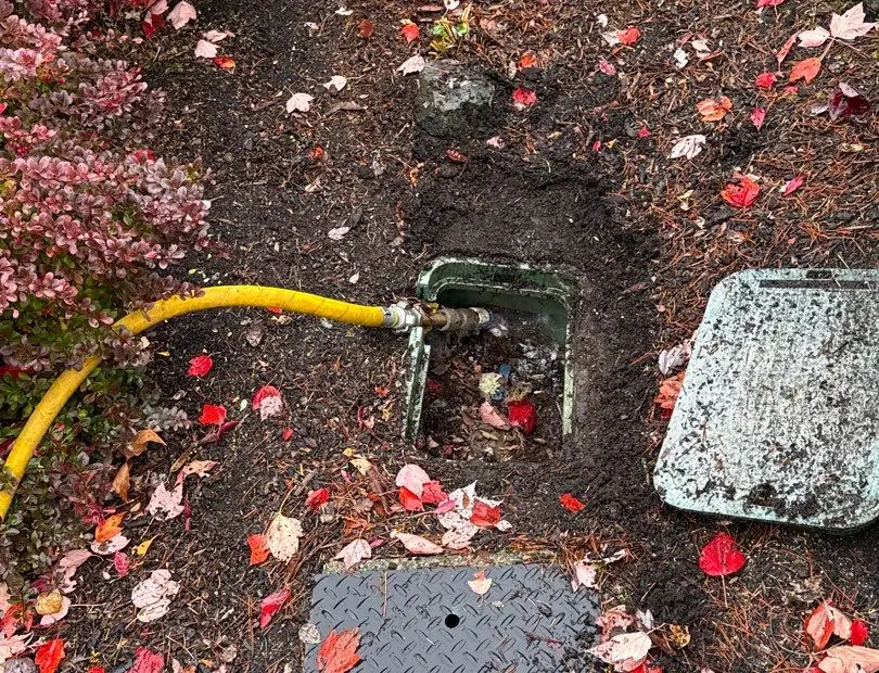 The compressor's yellow hose connected to the blowout port inside an open valve box, with the box lid set aside